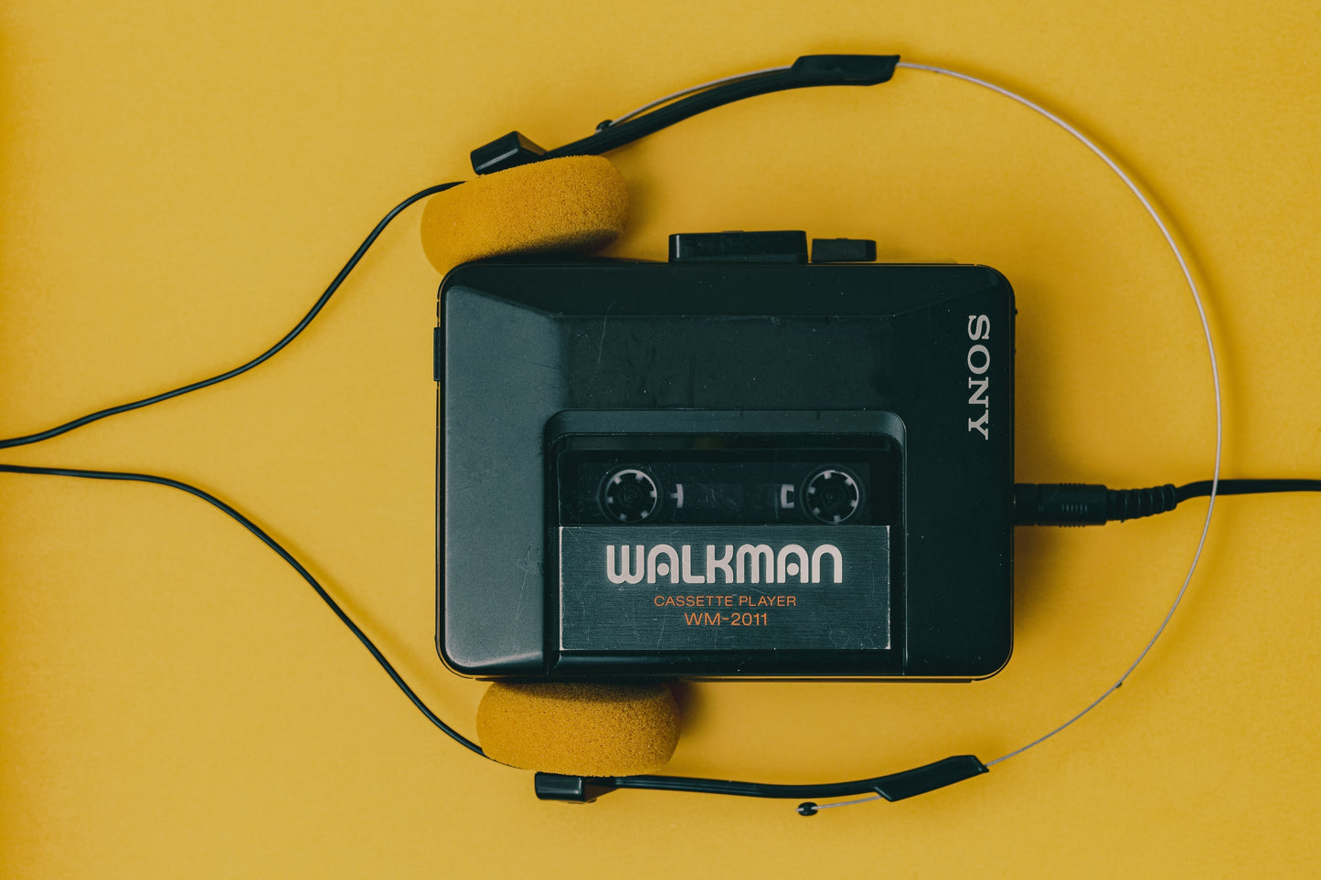 Walkman cassette player with headphones on a yellow background