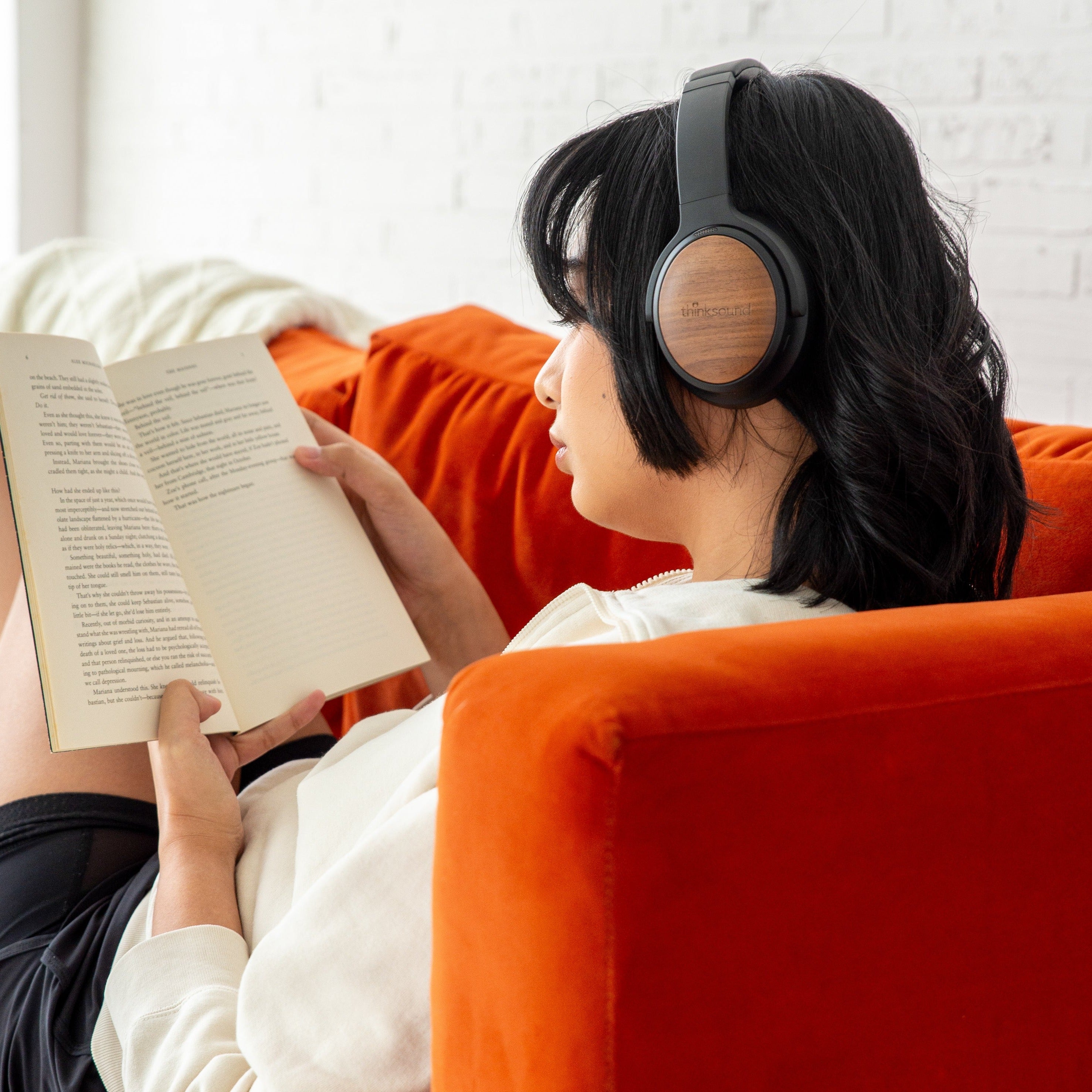 Person reading while wearing thinksound ov202w wireless over-ear headphones